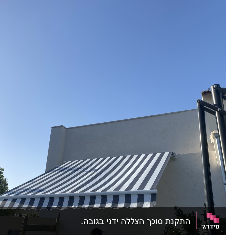 סוכך פסים לבן כחול מותקן על קיר חיצוני